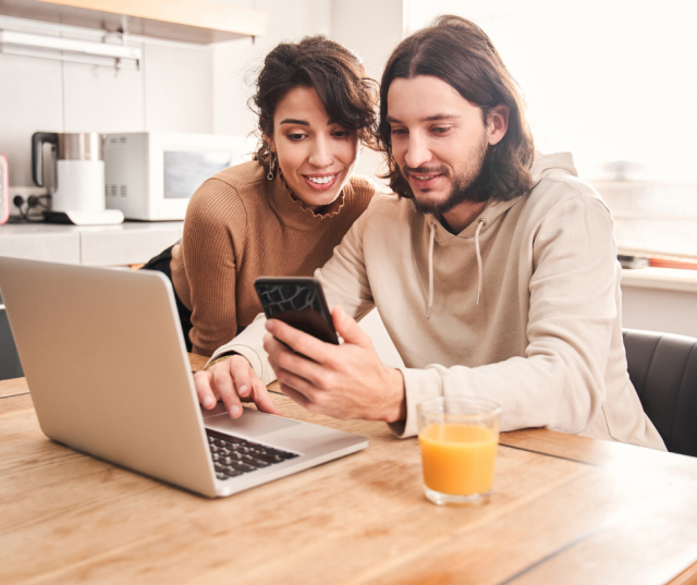 Un couple heureux pose une enchère sur un bien immobilier sur le site de vente immobilière en ligne Biddit.be.